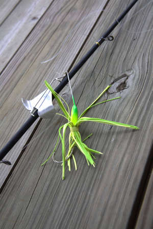 Fishing lure hooked to a black fishing pole. の写真素材
