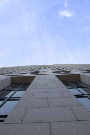 Looking straight up the side of a high-rise building towering into the sky.の写真素材