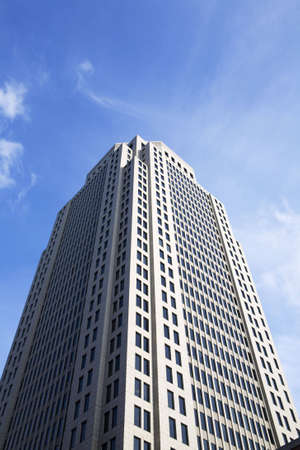 Towering high rise skyscraper on a deep blue sky with wispy clouds.の写真素材