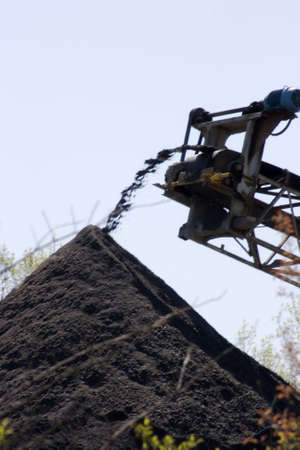 Moving dirt through an automated conveyor belt system. Conceptualization of the ease of digging up the natural order and discarding it to a pile of dirt. Motion blur of dirt exiting the conveyer.の写真素材