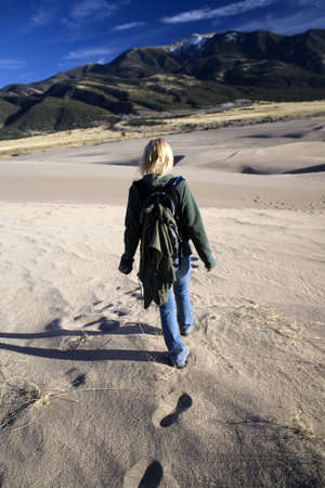 Woman walking away across a sandy landscape の写真素材