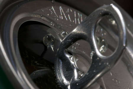Macro close-up shot of the top of an aluminum can. Shadowed lid with drops of beverage around...