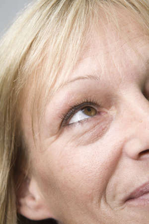 Closeup to right half of a female face. Woman is grinning while looking up. の写真素材