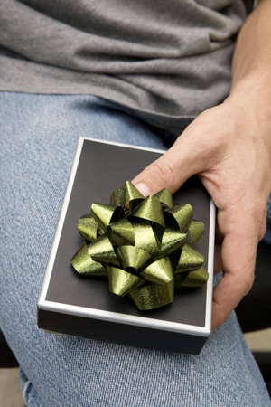 Man holding a small gift box with bow on his leg.の写真素材