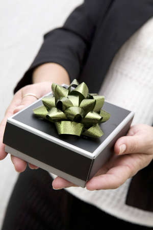 Woman holding a small gift bow with bow in outstretched arms.の写真素材