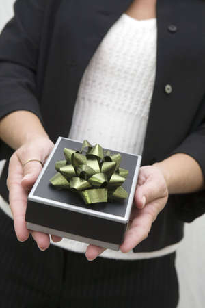 Woman holding a small gift bow with bow in outstretched arms.の写真素材