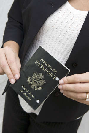 Woman holds out diplomatic passport for inspection in travling internationally.の写真素材