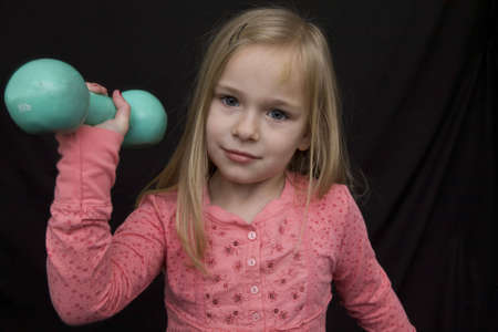 A young girl lifting a five pound dumbell in an attempt to workout and maintain fitnessの写真素材