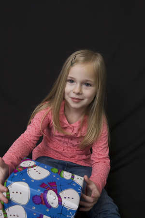 Young girl sitting with a Christmas present on her leg and smilingの写真素材