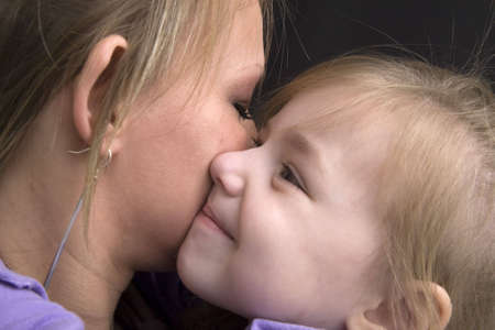 Closeup profile face view of mother and daughter in a tight embrace.の写真素材