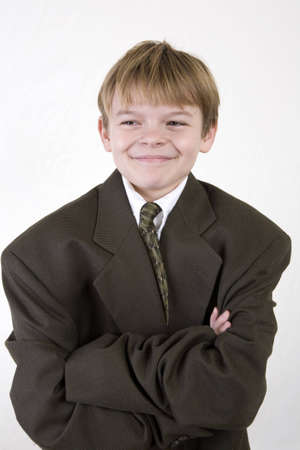Young boy expressing smug satisfaction at being dressed up in his dads business suitの写真素材