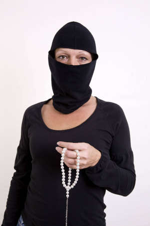 Female jewel theif holding a strand of pearls in her hand. Isolated on white background.の写真素材