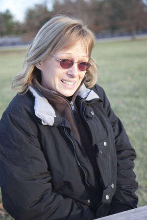 A woman sitting at a bench in a park with a look of disbelief on her face. の写真素材