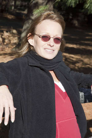 Adult woman in relaxed pose leaned against a wooden fence in an outdoor winter setting.の写真素材