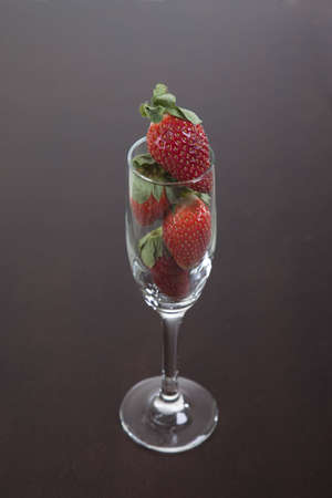 A champagned flute filled with strawberries on a wooden tableの写真素材