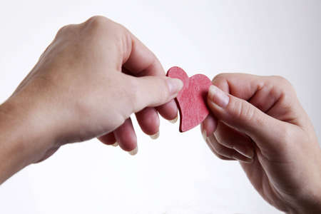 hands exchanging a red wooden heart symbolの写真素材
