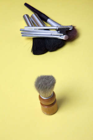 The pile of brushes needed for a woman to get ready to go out constrasted by the solitary shaving brush used by a man.の写真素材