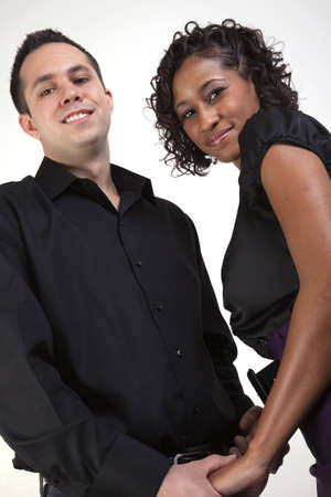 Interracial couple holding hands and smiling while facing each other