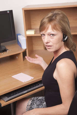 Business woman showing surprise at being laid off with a pink slip on her deskの写真素材