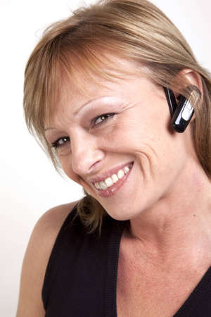 A beautiful mature woman with a wireless earpiece and head tilted to sideの写真素材
