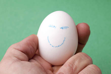 An egg decorated in blue crayon with a happy smiley face.