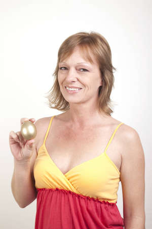 An adult female in a sundress showing her golden eggの写真素材