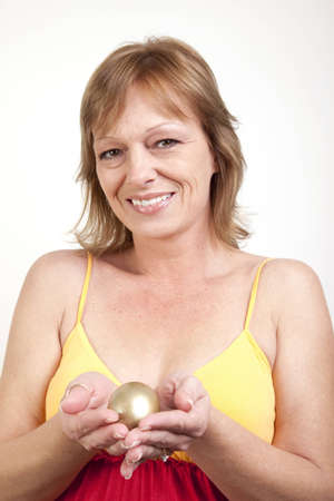 A mature woman cradling her golden egg in her handsの写真素材