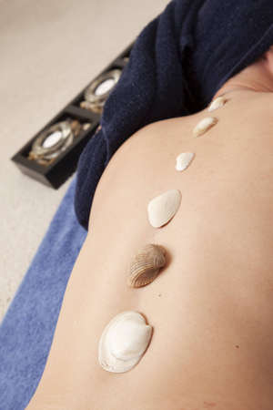 Seashells placed down the spine of a woman laying on a towel for relaxationの写真素材