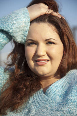 A plus size woman holding her hair while outsideの写真素材