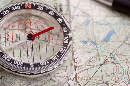 A compass on a topographical map showing terrain featuresの写真素材
