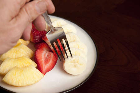Picking up a slice of fresh banana on a forkの写真素材