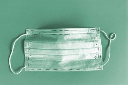 Protective mask on green background. Disposable surgical face mask cover mouth and nose. Healthcare medical Coronavirus quarantine, hygiene concept. Prevent coronavirusの写真素材