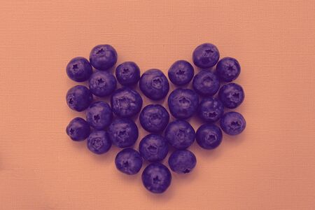 Blueberries in the shape of heart on a yellow background. The concept: blueberries prevent heart disease. Tonned.の写真素材
