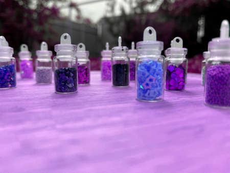 Colorful glitters for nail art and makeup in small glass jars isolated