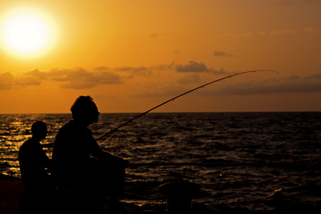 Two fishermen on sunset backgroundの写真素材