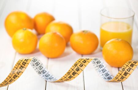 Measure tape with oranges and juice blurred on wooden white backgroundの写真素材
