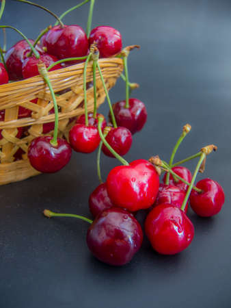 fresh red cherries on a basket on black backgroundの写真素材