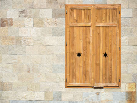 closed wooden window on a rocky wallの写真素材
