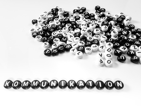 heap of round letters black and white and communication word written in german written by side; kommunikationの写真素材