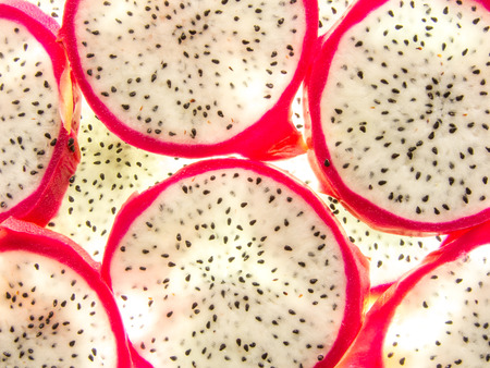 background of back lit fresh ripe pitaya dragon fruit slicesの写真素材
