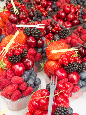 assorted forest fruits in plastic casserole at the marketの写真素材