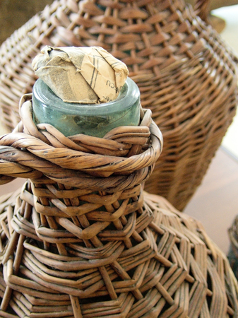 glass demijohn wrapped in straw basket traditional alcohol different liquids storage