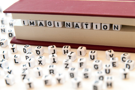 Word imagination written with letters between a book pages white background with letters spread around education reading conceptの写真素材