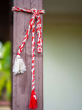 red and white knitting string tied up on house wooden pillar martisor romanian 1st of march...