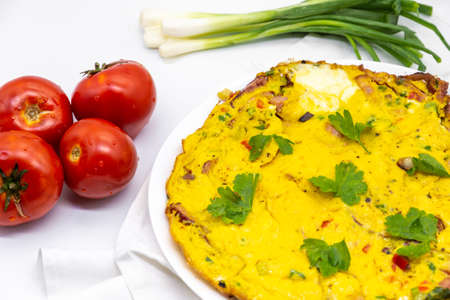 delicious omelette served served with fresh green onion and tomatoes on white decorの写真素材