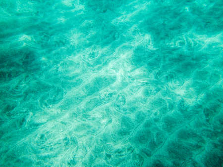 underwater scene in shallow waters with light rays on ocean seabedの写真素材