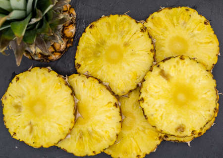 sliced pineapple arranged on black slateの写真素材