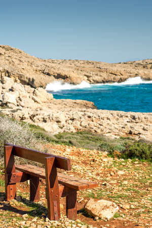 wooden bench near rock sea shoreの写真素材
