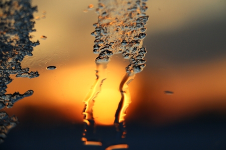 Sunrise behind frozen water on a windowの写真素材