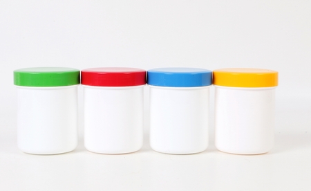 small white plastic tins with colorful caps are standing in the studio in a rowの写真素材